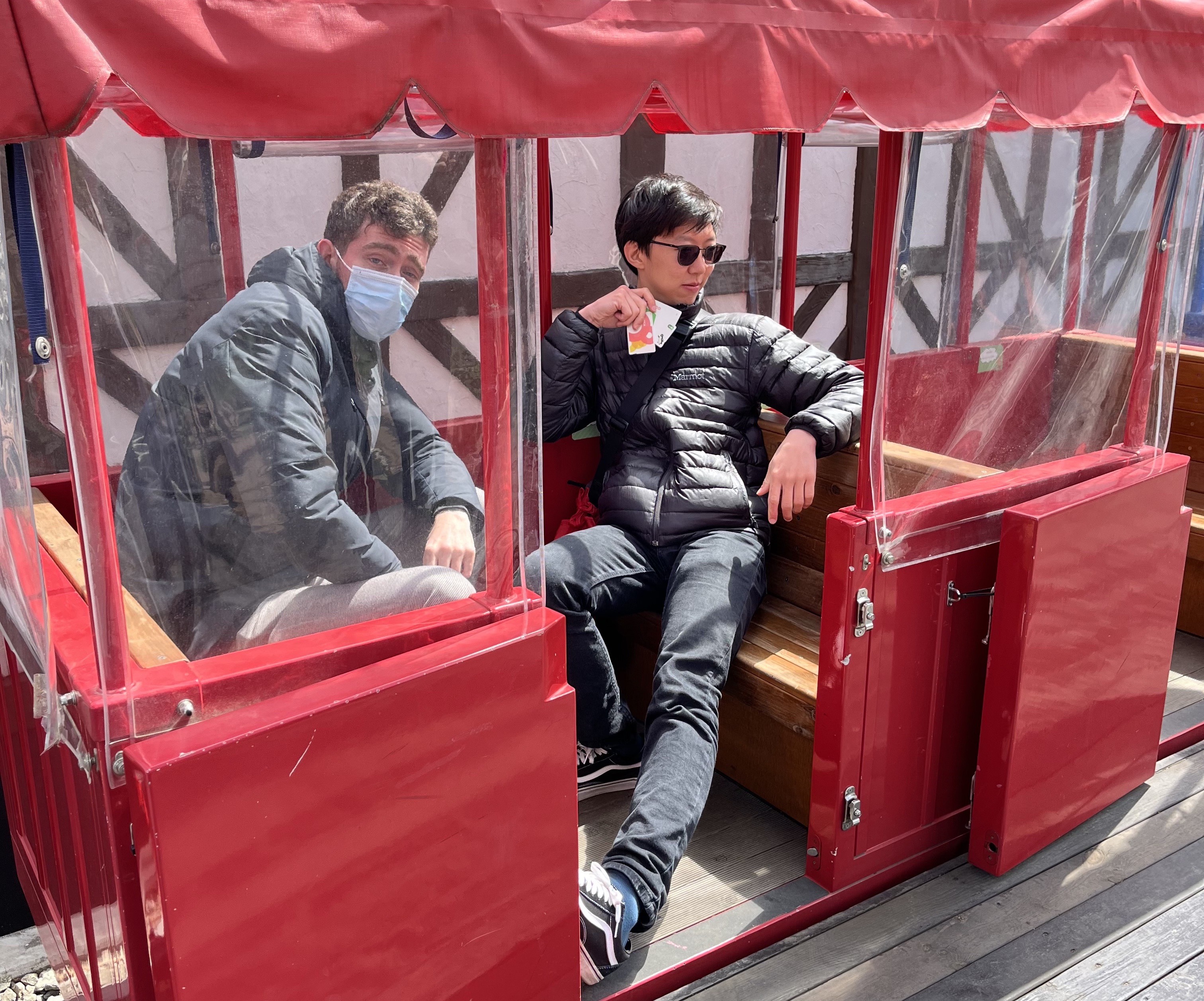 Me posing in a mini-train display, holding several Japanese transit cards in my hand.